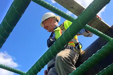 EIV Worker on beams against a bright blue sky.